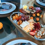 Elegant charcuterie board featuring cheeses, fruits, and nuts on a fall-themed table setting.